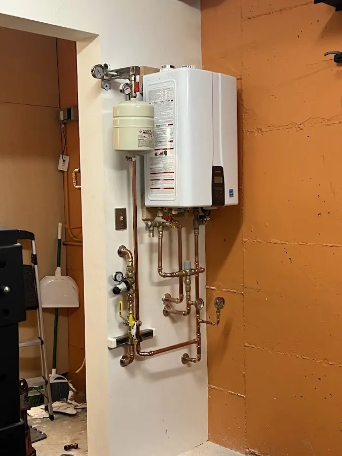 Plumbing technician inspecting water heater connections in Acton